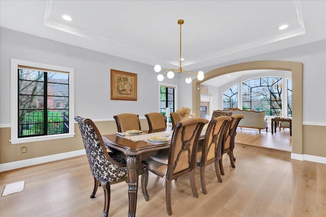 dining area with light hardwood / wood-style flooring, a raised ceiling, and a healthy amount of sunlight