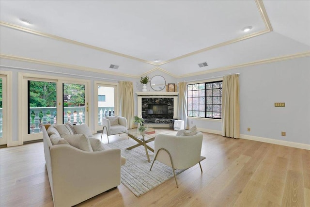 living room with a premium fireplace, ornamental molding, lofted ceiling, and light hardwood / wood-style flooring