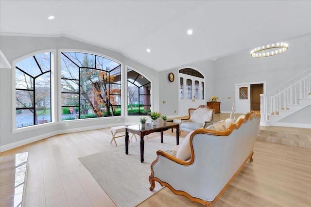 living room featuring light wood-type flooring, ornamental molding, and a notable chandelier