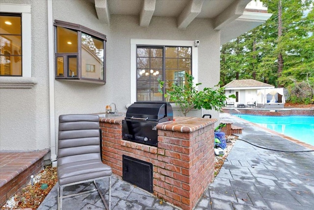 view of patio featuring a grill, an outbuilding, and an outdoor kitchen