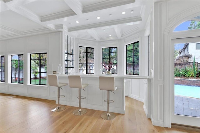 kitchen featuring white cabinets, light hardwood / wood-style flooring, beam ceiling, a breakfast bar area, and coffered ceiling