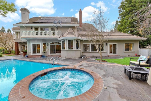 back of property with a balcony, a patio area, and solar panels