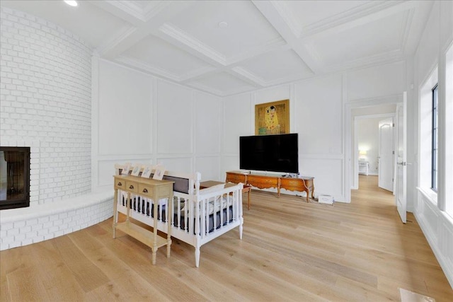 bedroom with hardwood / wood-style floors, coffered ceiling, beam ceiling, and a fireplace