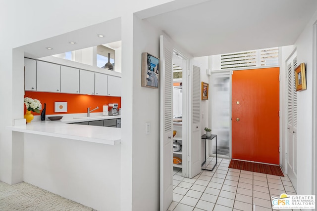 kitchen with white cabinets, sink, kitchen peninsula, and light tile patterned flooring