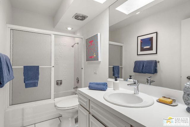 full bathroom with a skylight, vanity, shower / bath combination with glass door, tile patterned flooring, and toilet