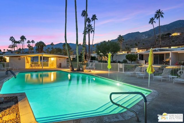 pool at dusk featuring a mountain view and a patio