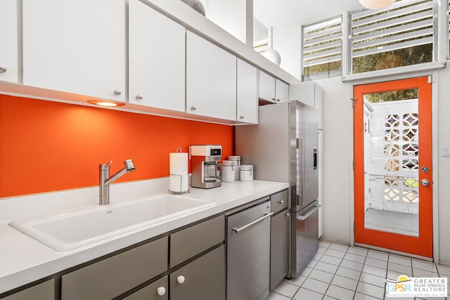 kitchen featuring sink, white cabinetry, stainless steel appliances, and light tile patterned floors