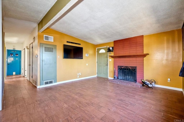 unfurnished living room with a brick fireplace, lofted ceiling with beams, and a textured ceiling