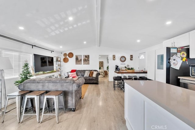 living room with light hardwood / wood-style floors and vaulted ceiling with beams