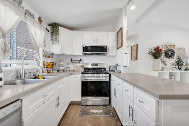 kitchen with white cabinets, appliances with stainless steel finishes, dark hardwood / wood-style flooring, sink, and lofted ceiling with beams