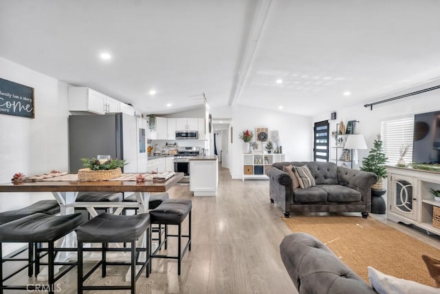 living room featuring vaulted ceiling with beams and light hardwood / wood-style floors