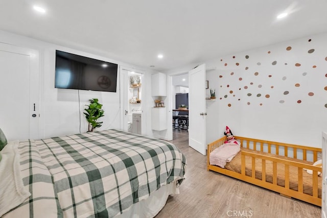 bedroom with ensuite bathroom and light wood-type flooring