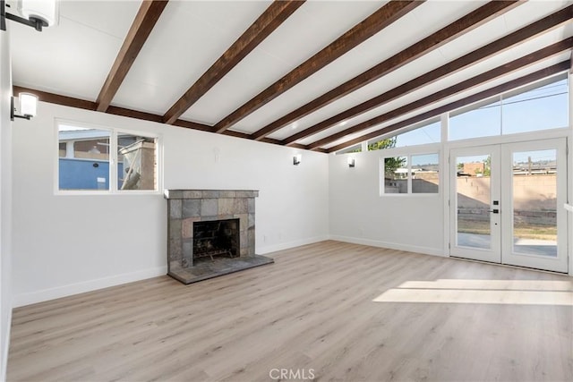 unfurnished living room featuring a fireplace, french doors, light wood-type flooring, and vaulted ceiling with beams