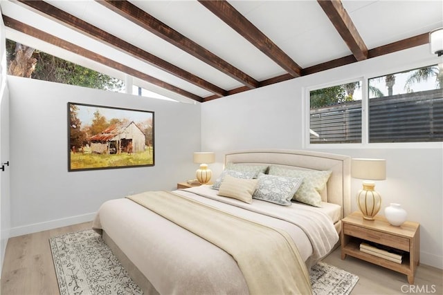 bedroom with lofted ceiling with beams, light hardwood / wood-style floors, and multiple windows