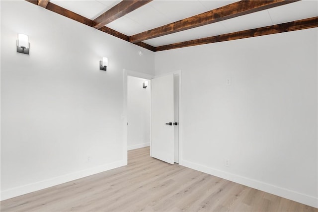 empty room with beam ceiling and light wood-type flooring