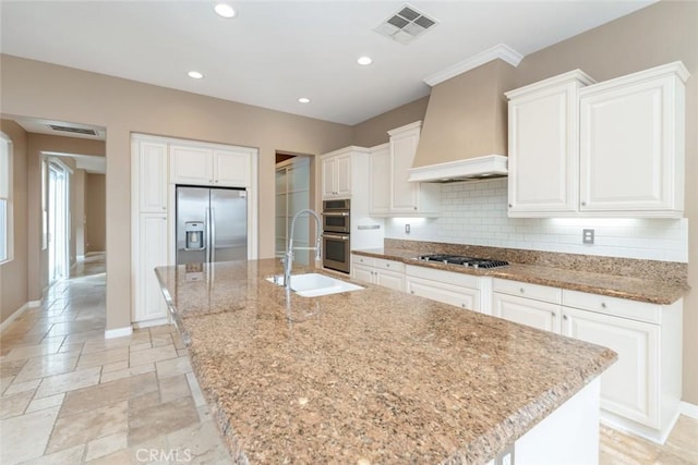 kitchen featuring a kitchen island with sink, sink, stainless steel appliances, and custom exhaust hood