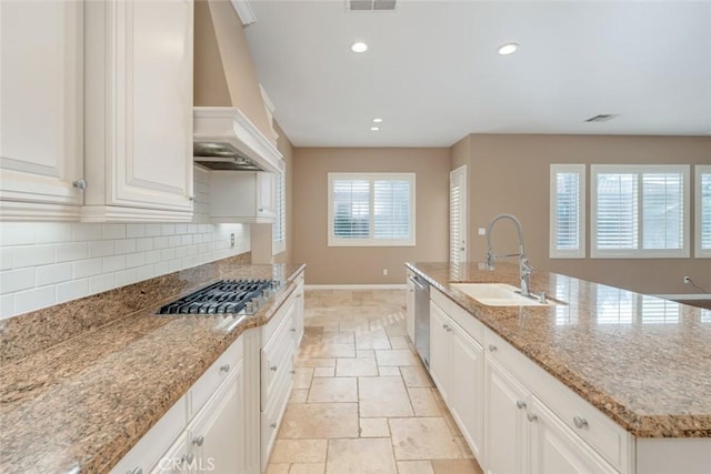 kitchen with appliances with stainless steel finishes, backsplash, custom range hood, sink, and white cabinetry