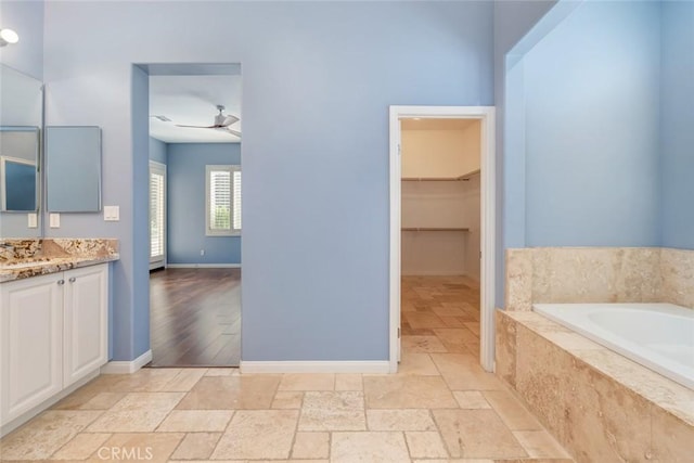 bathroom with vanity, tiled bath, and ceiling fan