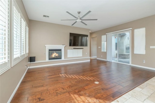 unfurnished living room featuring plenty of natural light, ceiling fan, and wood-type flooring