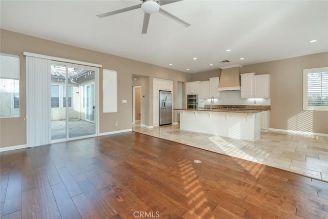 kitchen featuring stainless steel appliances, light hardwood / wood-style floors, a breakfast bar, white cabinets, and custom exhaust hood