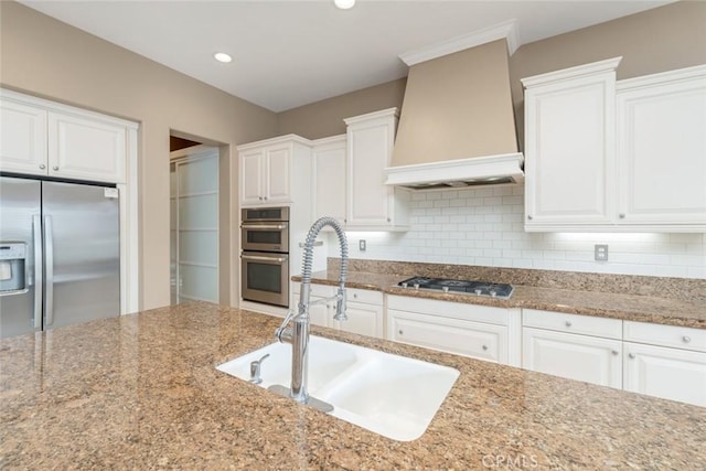 kitchen featuring white cabinets, custom exhaust hood, sink, and appliances with stainless steel finishes