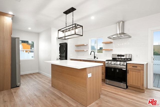 kitchen with plenty of natural light, light hardwood / wood-style floors, wall chimney range hood, and stainless steel appliances