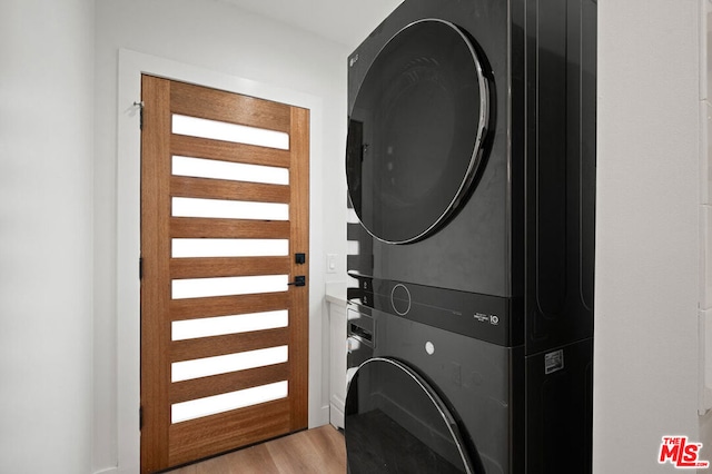 clothes washing area with light hardwood / wood-style floors and stacked washer and clothes dryer