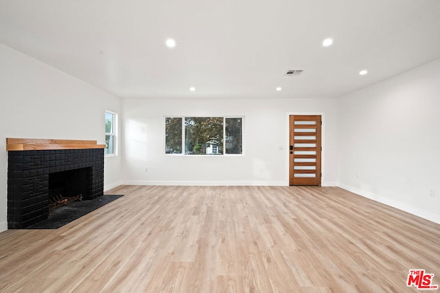 unfurnished living room featuring a fireplace and light hardwood / wood-style flooring