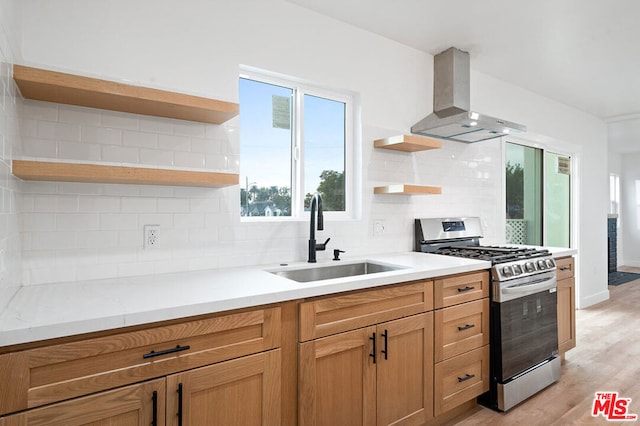 kitchen featuring gas range, sink, wall chimney range hood, tasteful backsplash, and light hardwood / wood-style floors