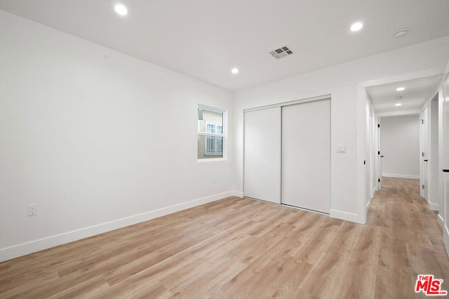 unfurnished bedroom featuring a closet and light wood-type flooring