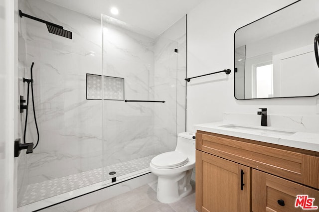 bathroom with tiled shower, vanity, and toilet