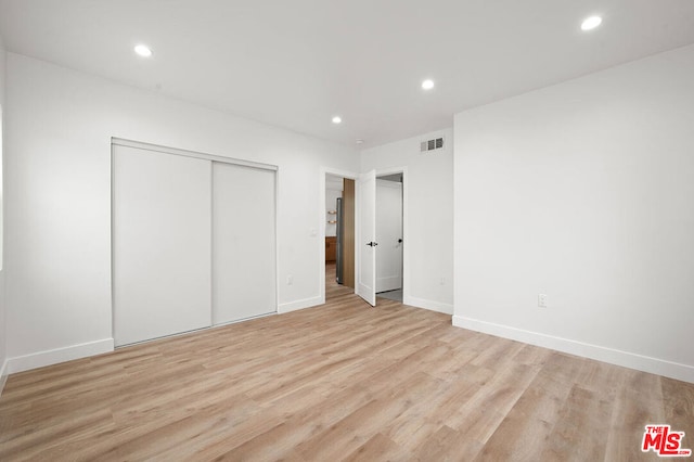 unfurnished bedroom featuring light hardwood / wood-style flooring and a closet