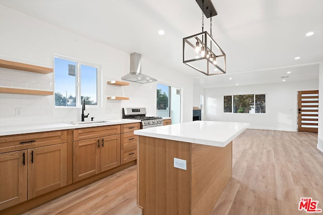 kitchen with gas range, light hardwood / wood-style floors, wall chimney exhaust hood, and sink