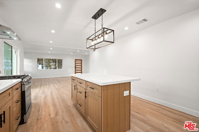 kitchen with stainless steel range with gas cooktop, light hardwood / wood-style flooring, a kitchen island, and hanging light fixtures