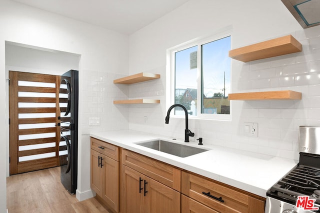 kitchen with tasteful backsplash, light hardwood / wood-style floors, stainless steel gas range oven, and sink