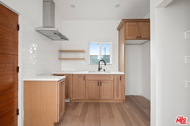 kitchen featuring light wood-type flooring, tasteful backsplash, wall chimney exhaust hood, and sink