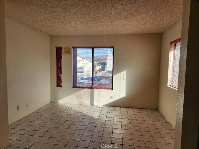 spare room with light tile patterned floors and a textured ceiling