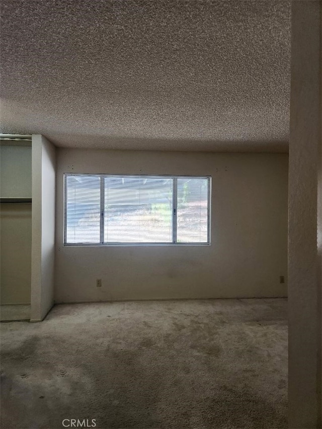 carpeted spare room featuring a textured ceiling