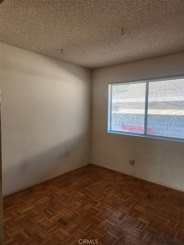 spare room with dark parquet flooring and a textured ceiling