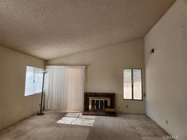 unfurnished living room with light colored carpet, a textured ceiling, and vaulted ceiling