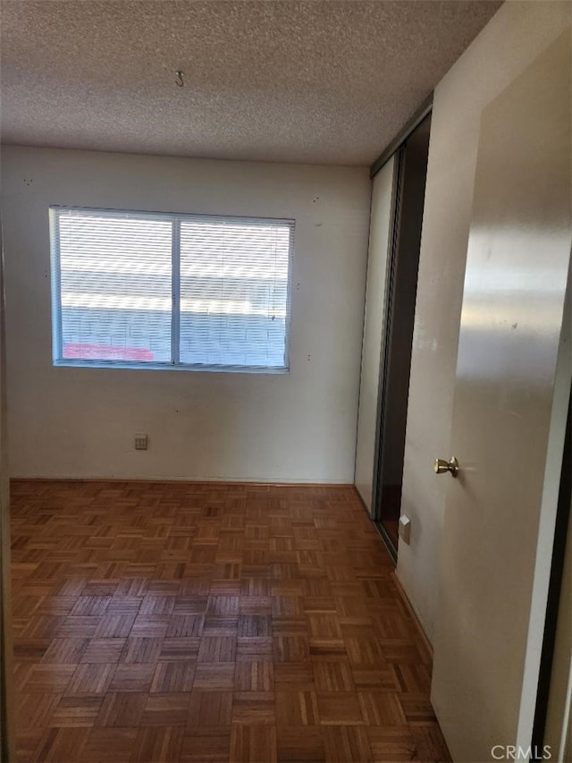 empty room with a textured ceiling and dark parquet floors