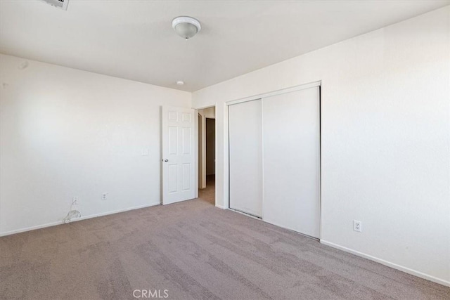 unfurnished bedroom featuring light colored carpet and a closet