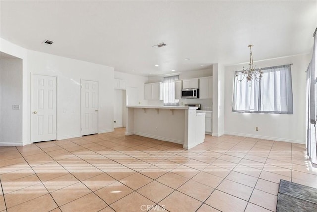 kitchen featuring a healthy amount of sunlight, a kitchen bar, white cabinetry, and an inviting chandelier