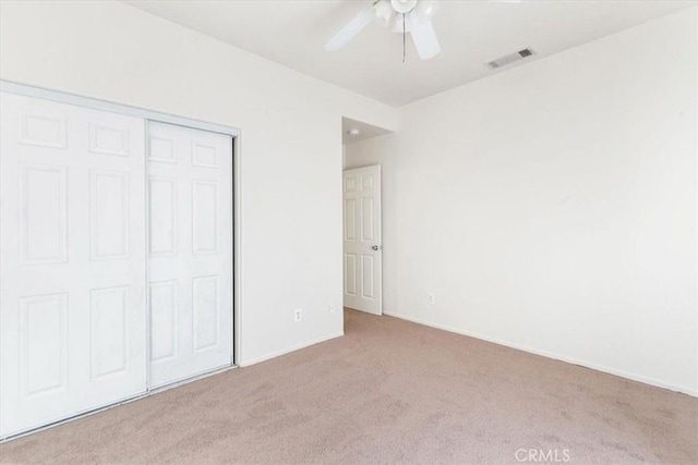 unfurnished bedroom featuring ceiling fan, a closet, and light colored carpet