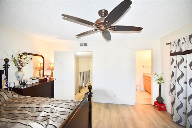 bedroom featuring ensuite bathroom, ceiling fan, light hardwood / wood-style floors, and a textured ceiling