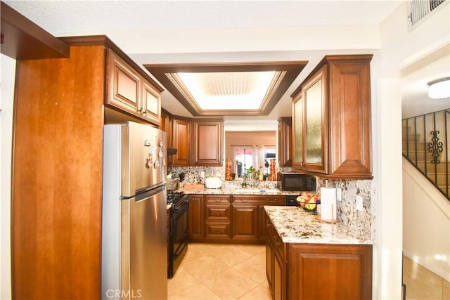 kitchen featuring light stone countertops, backsplash, sink, black appliances, and light tile patterned flooring