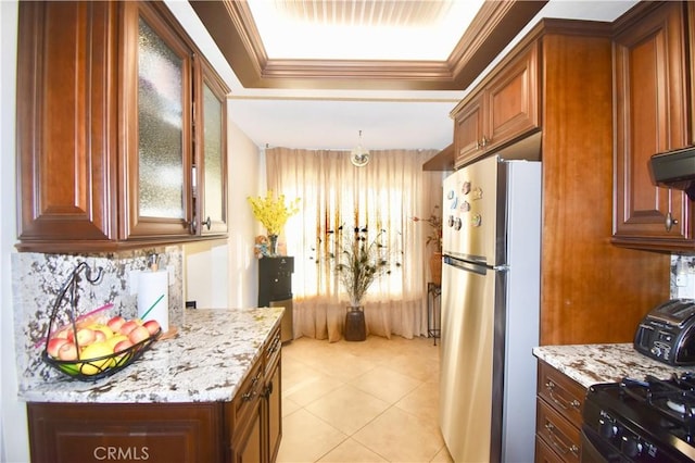 kitchen featuring light stone counters, ornamental molding, and stainless steel refrigerator