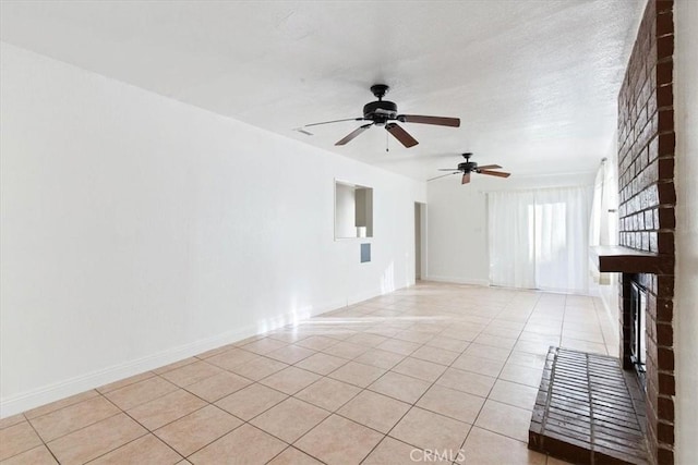 empty room with a fireplace, ceiling fan, and light tile patterned flooring