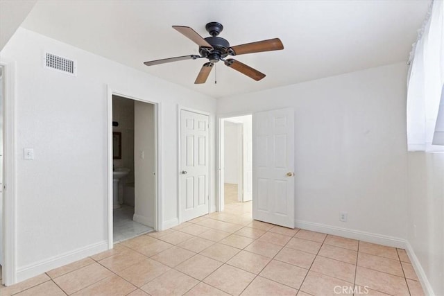 unfurnished bedroom featuring light tile patterned floors, a closet, ensuite bath, and ceiling fan