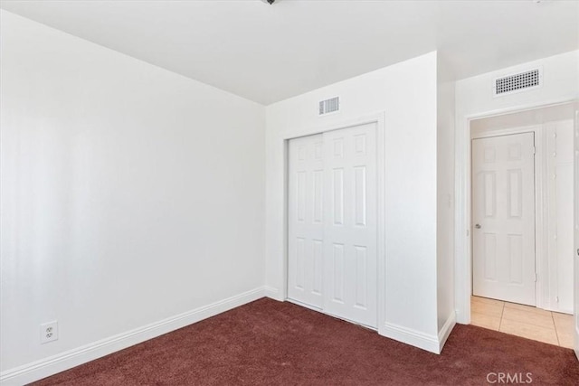 unfurnished bedroom featuring dark carpet and a closet